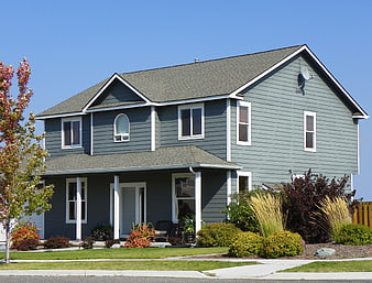 Modern gray suburban house with white trim and blue sky