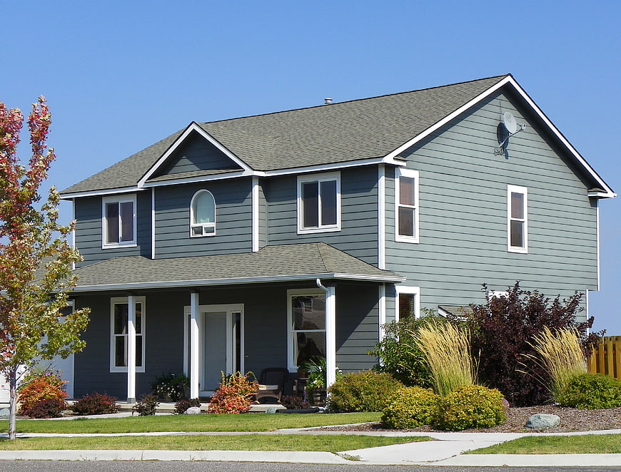 Modern gray suburban house with white trim and blue sky