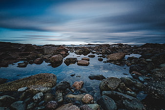 Dramatic rocky coastline with tide pools and moody blue sky