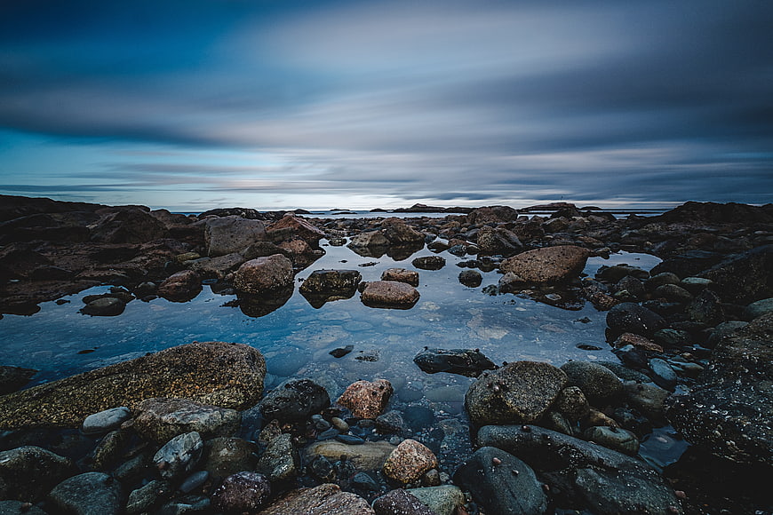 Dramatic rocky coastline with tide pools and moody blue sky