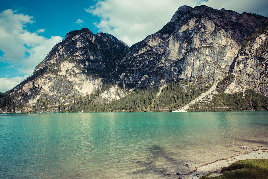 Turquoise alpine lake with rocky mountains and pine forest
