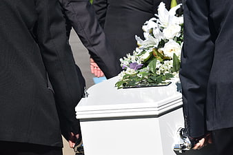 Pallbearers carrying white coffin with flowers at funeral