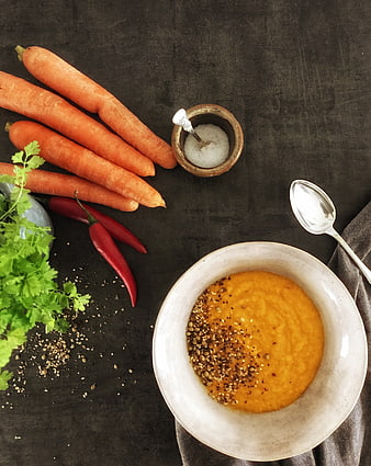 Overhead view of creamy carrot soup with fresh ingredients