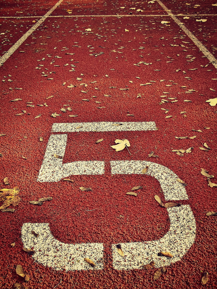 Number 5 on Red Running Track with Autumn Leaves