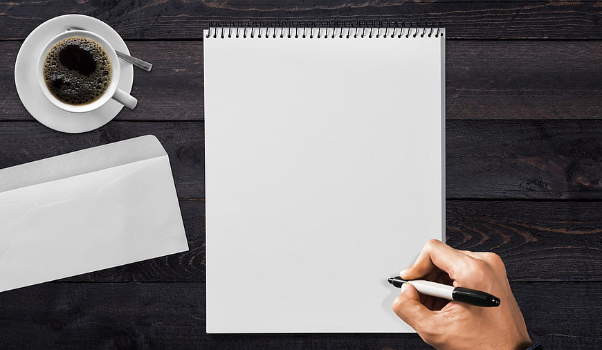 Top View of Hand Writing on Notepad with Coffee and Envelope