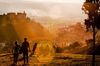 Silhouetted Group Watching Golden Sunset Over Historic City