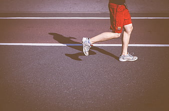 Runner's legs and shadow on track
