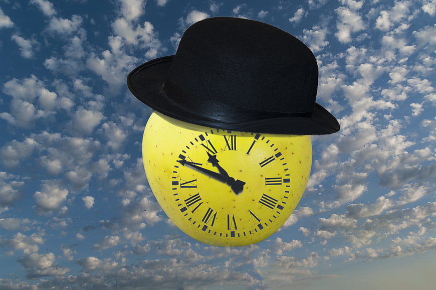 Yellow clock with black hat against blue sky