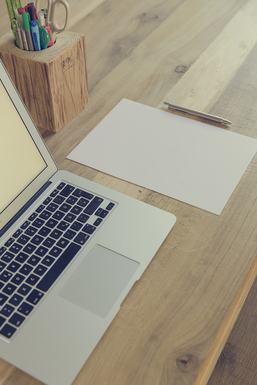 Minimalist wooden workspace with laptop and blank paper