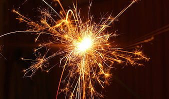 Golden Sparkler Bursting With Bright Sparks Against Dark Background