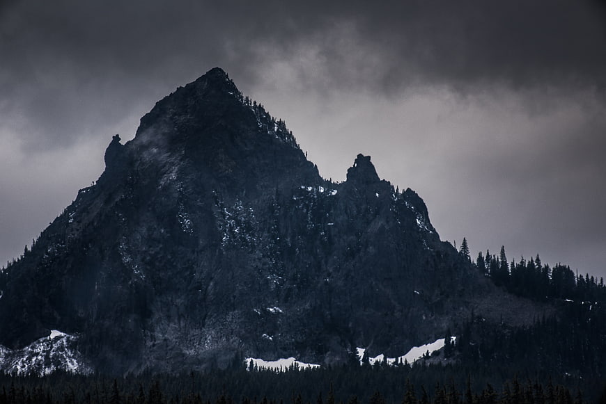 Dark Stormy Mountain Peak with Snow and Pine Trees