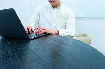 Man Typing on Laptop at Dark Wooden Desk