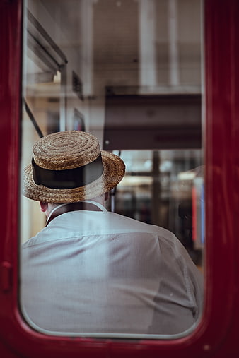Man in Straw Hat Looking Out Train Window