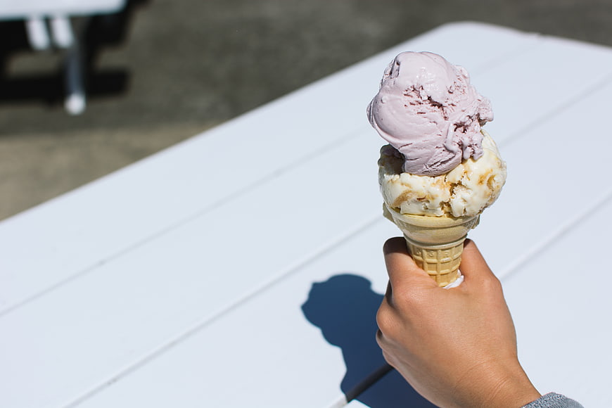 Hand holding two scoops of ice cream on white table