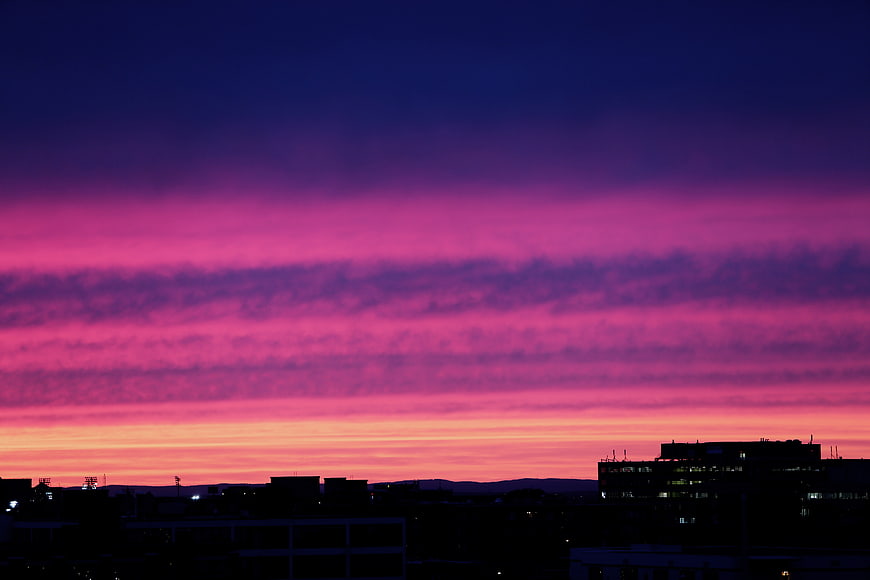 Vibrant Pink and Purple Sunset Sky Over City Silhouette