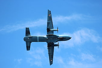Military P-3 Orion aircraft flying overhead against blue sky
