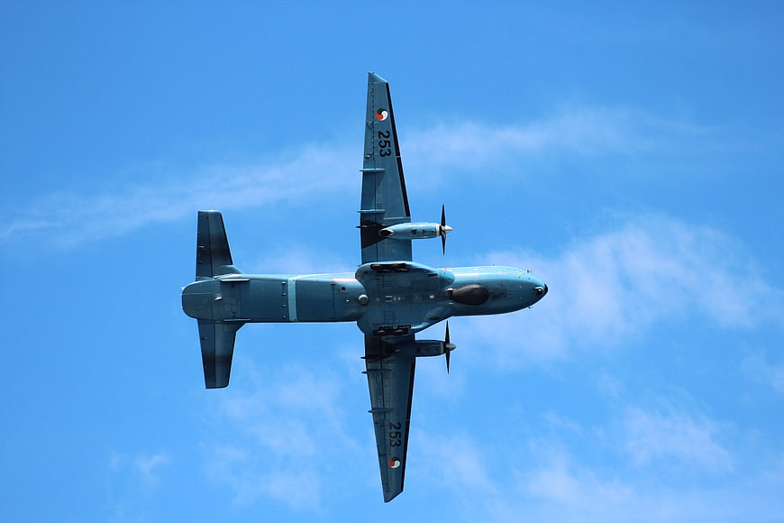 Military P-3 Orion aircraft flying overhead against blue sky
