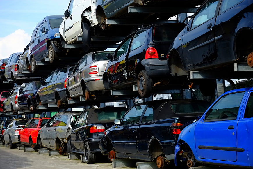 Stacked damaged cars in a scrapyard with rust and missing wheels