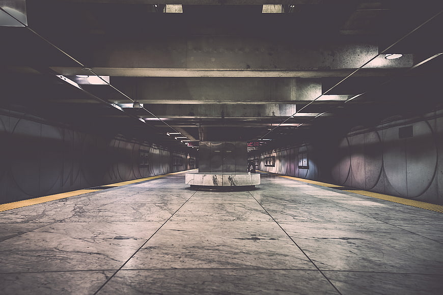 Empty underground subway station with marble floor and concrete pillars