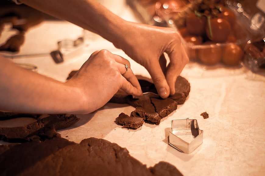 Hands cutting gingerbread dough with cookie cutter