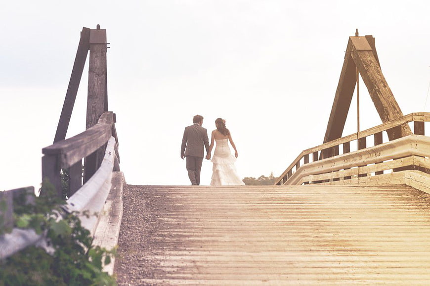 Bride and Groom Walking Away on Wooden Bridge