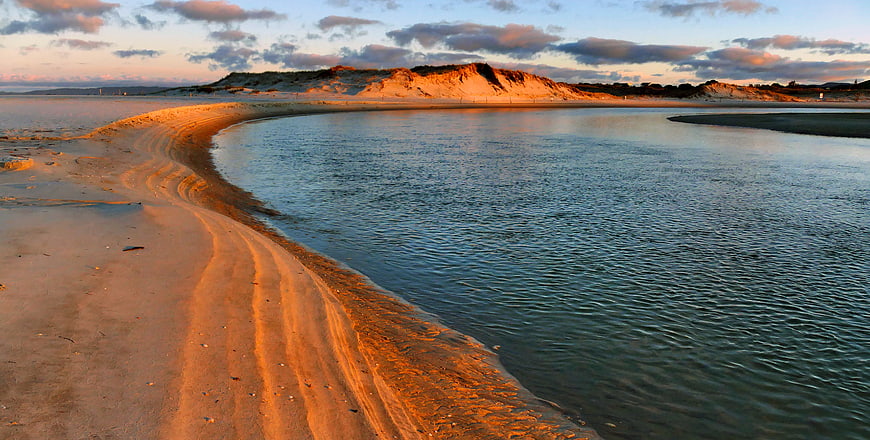 Golden Sunset on Sandy Beach with Calm Water and Dunes