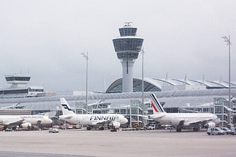 Airplanes parked at Munich Airport tarmac with control tower