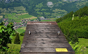 Wooden suicide platform overlooking green alpine valley village
