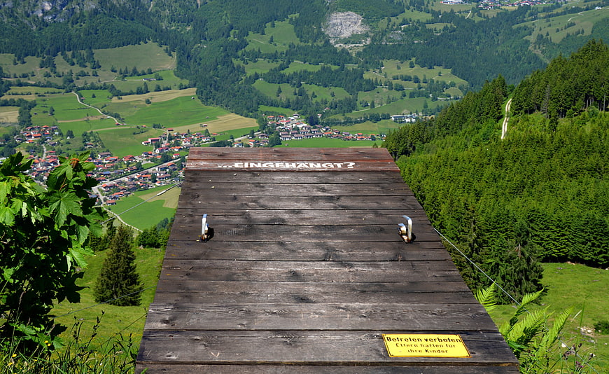 Wooden suicide platform overlooking green alpine valley village