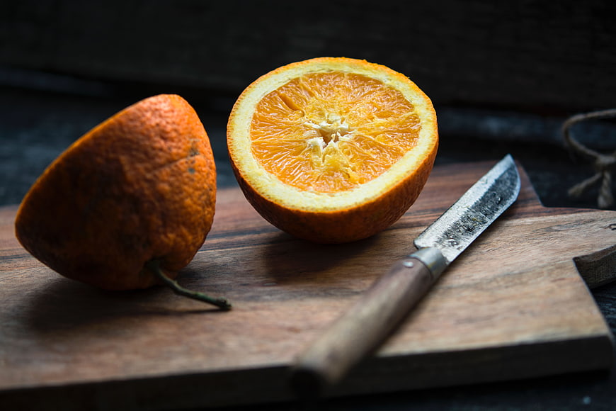 Fresh Cut Orange on Wooden Board with Knife
