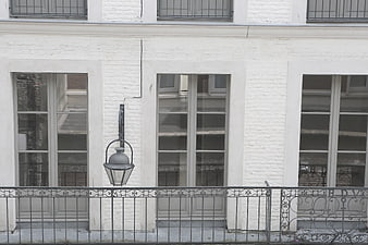 White brick building facade with windows and balcony railing