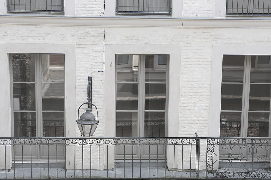 White brick building facade with windows and balcony railing