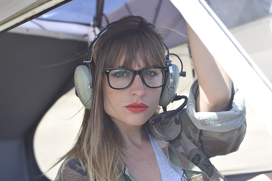 Female pilot with headset and glasses in aircraft cockpit