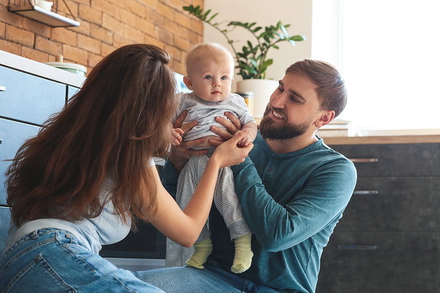Happy Parents Holding Baby in Modern Kitchen Interior