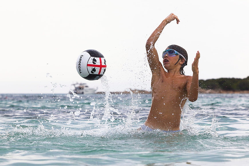 Boy playing water polo in the sea with ball