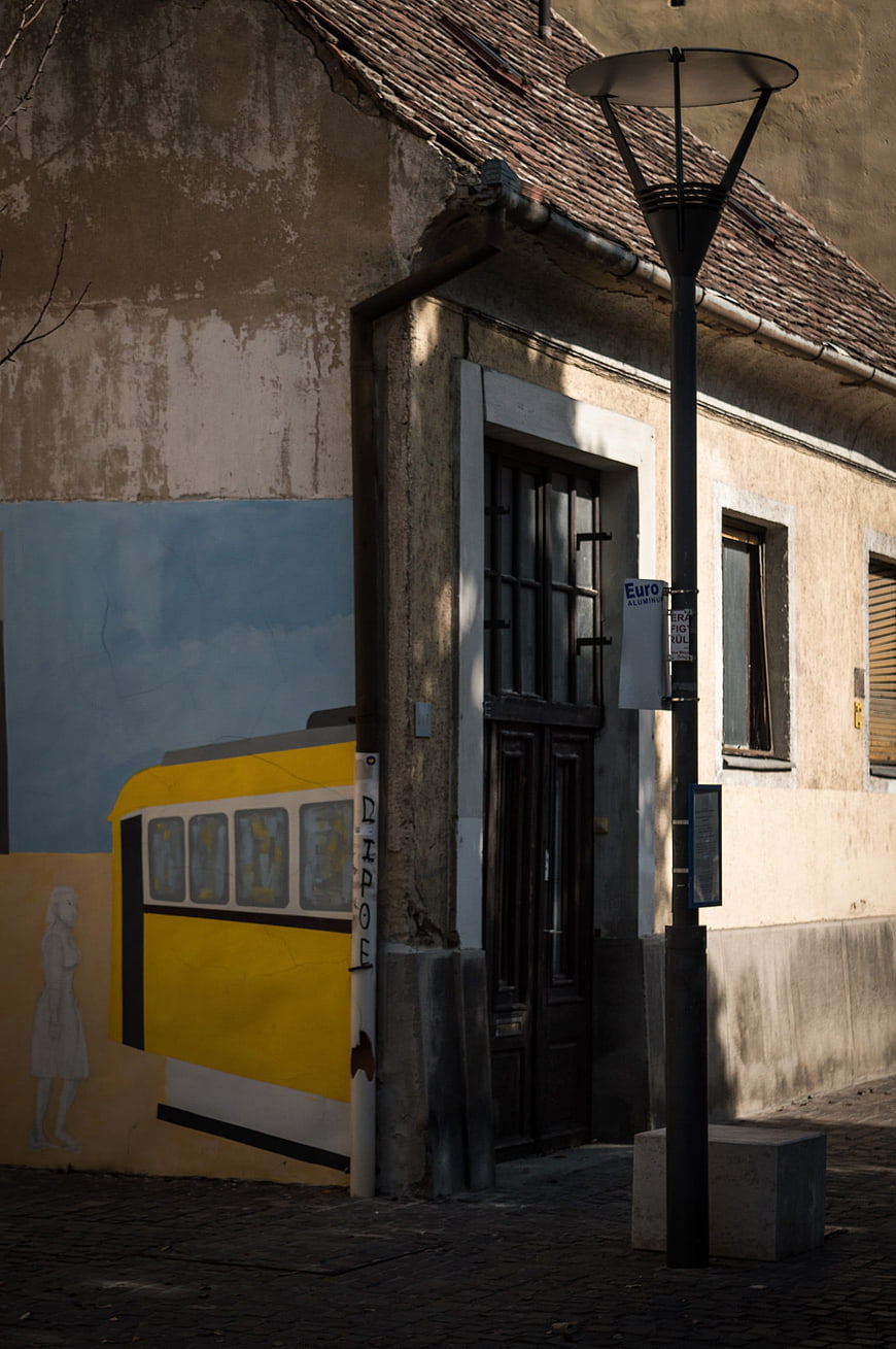 Yellow tram mural on weathered building wall