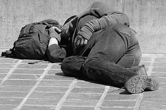 Black and white photo of homeless man sleeping on pavement