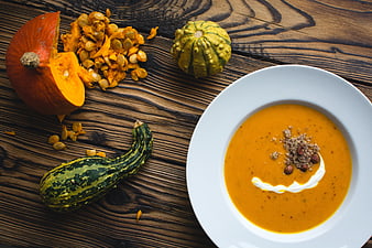 Overhead view of creamy pumpkin soup with roasted seeds and fresh squash on rustic wood