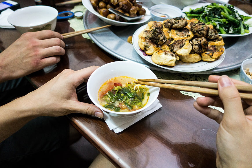 Hands eating Vietnamese fish soup with chopsticks