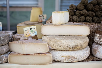 Stacked artisanal French cheeses at a market display