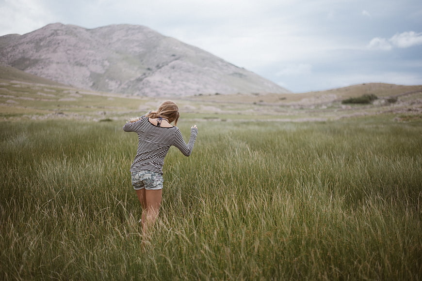 Woman hiking in grassy highland landscape with mountains