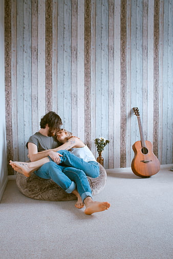 Couple Embracing on Floor Cushion with Acoustic Guitar in Rustic Room