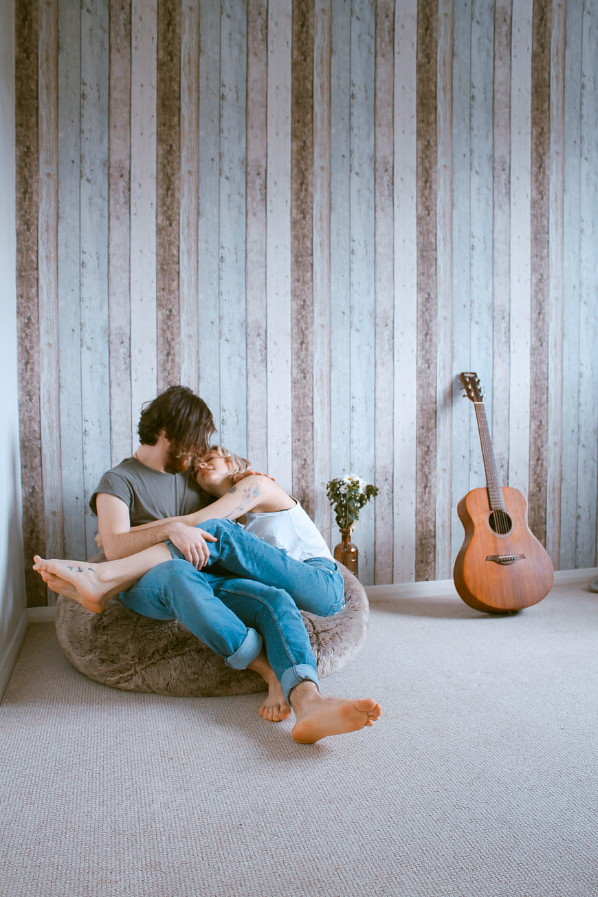 Couple Embracing on Floor Cushion with Acoustic Guitar in Rustic Room