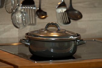Dark enameled Dutch oven with glass lid on modern induction cooktop