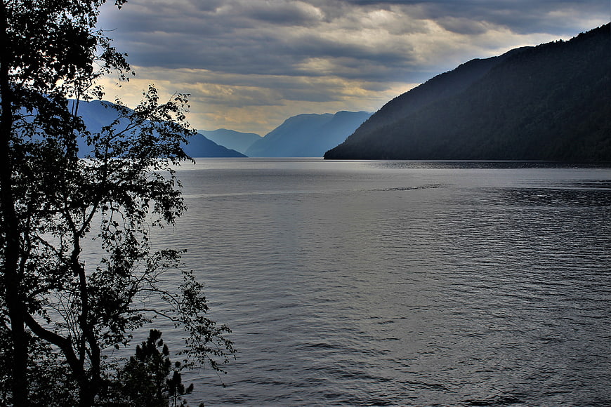 Serene Lake Landscape with Silhouetted Trees and Mountains