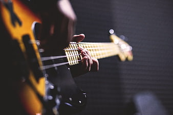 Close-up of hands playing electric guitar on dark background