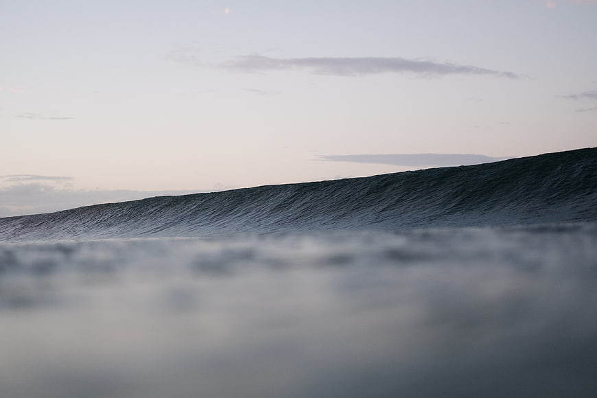 Smooth ocean wave at dusk with blurred foreground