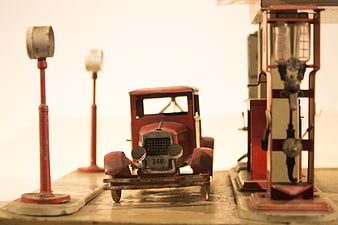 Vintage red toy car at retro gas station diorama