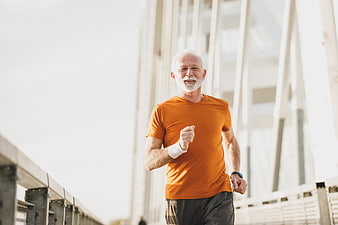 Senior man jogging on bridge in orange shirt