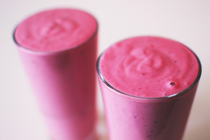 Two Pink Strawberry Smoothies In Clear Glasses